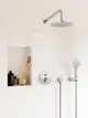 Moderne Dusche mit runder Regendusche, Wandhalterung und Handbrause. Wand mit hellen, schräg verlegten Fliesen, Nische zur Aufbewahrung von Pflegeprodukten, gestaltet von Ideal Standard.